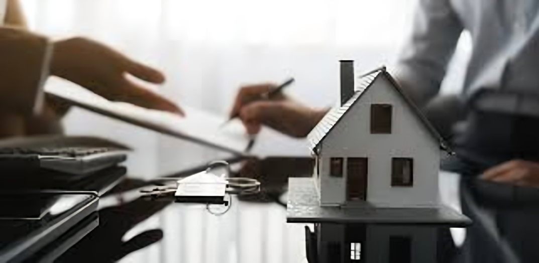 A person signing real estate documents near model house